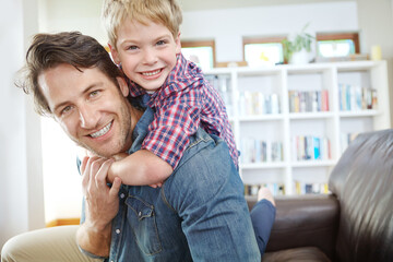 Canvas Print - Portrait, father and son on sofa with piggyback, bonding and love in living room for playful family in home. Relax, dad and child on couch for happy weekend together with fun, smile and embrace.