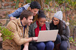 © peopleimages.com - College, students and talking with laptop on campus for communication, learning or knowledge. Education, diversity and friends on stairs with technology for assignment, study group or search internet