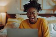 © DK_2020 - A young woman laughing at something on her laptop screen capturing a moment of leisure and enjoyment at home