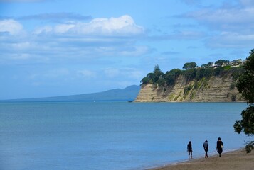 Wall Mural - Scenic view of three women walking on the beach in Auckland, New Zealand