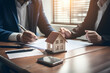 © Aishwa - Real estate professionals offer contracts to their clients to discuss home purchases, insurance, or real estate loans. Home sales agent sitting in an office with a new home buyer in the office