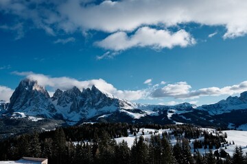 Wall Mural - Stunning view of Seceda mountain, framed by a beautiful blue sky and fluffy white clouds