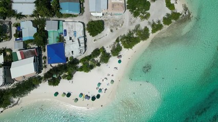 Wall Mural - Rotating drone footage over umbrellas sandy beach by turquoise sea water