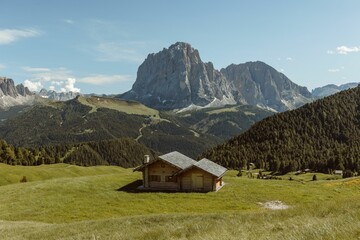 Wall Mural - Rustic log cabin nestled in the foothills on the background of the Seceda mountain