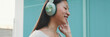 © Andrii Nekrasov - Happy beautiful brunette girl in headphones dressed in casual clothes, listens to music and singing along, Panorama