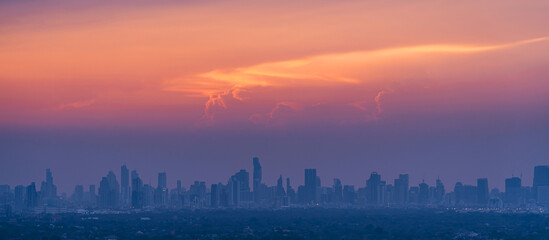 Wall Mural - Sunrise over modern office buildings in district center of Bangkok. Panoramic skyline view of cityscape with sunlight and flare in warm light color tone. Construction business concept.