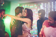 © peopleimages.com - Couple, kiss and dance in club at night on date with love in marriage or relationship. People, hug and embrace together in celebration at neon disco, party or rave at techno music festival in lights