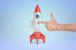 © gearstd - Hand points at rocket suggesting launch