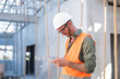 © Have a nice day  - Caucasian Male technician engineer construction worker working in building site wearing safety vest and helmet gears, using mobile smartphone technology with digital blueprint analyzing planning.