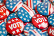 © Jennifer Clason - A pile of red, white, and blue buttons with the word 'VOTE' prominently displayed on them, emphasizing a patriotic theme