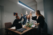 © qunica.com - A diverse group of colleagues enthusiastically high-fiving in an office, celebrating successful project completion.