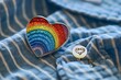 © Picasso - A rainbow heart shaped enamel pin resting on a blue shirt