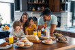 © Dorde - Happy family of four at the table eating breakfast.