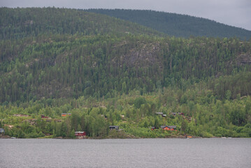 Scandinavian-style wooden houses at the foot of the Norwegian mountains on the shore of the lake