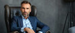 © RISHAD - Confident man with a beard, sitting in a leather with serious expression and stylish attire