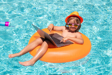 Business summer travel. Kid remote working on laptop in pool. Little business man working online on laptop in summer swimming pool water.