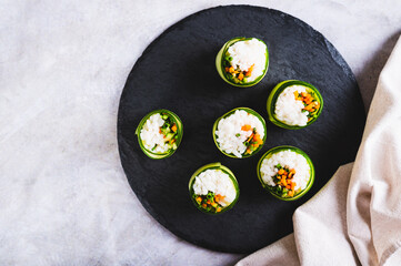 Canvas Print - Close up of vegetable sushi made of rice, cucumber and carrots on a slate board top view