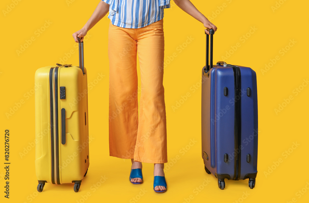 Young woman with suitcases on yellow background. Travel concept