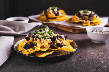 Poster - Mexican nacho chips baked with chicken, black beans and cheese on a plate on the table