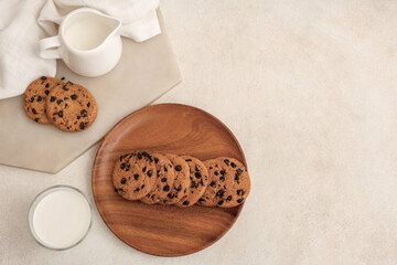 Sticker - Wooden plate and board of sweet cookies with chocolate chips and glass of milk on white background
