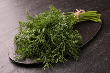 Bunch of fresh dill on dark textured table, closeup