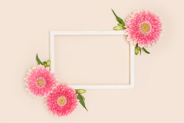 Wall Mural - frame made of green leaves and pink gerbera flowers on a beige background.