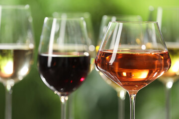 Different tasty wines in glasses against blurred background, closeup