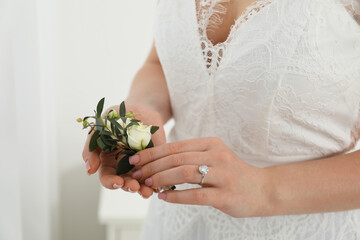 Wall Mural - Bride holding boutonniere for her groom on blurred background, closeup