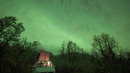 Wall Mural - A camper van with an open tent under the sky lit by the magnificent aurora. A timelapse video.