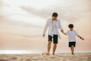 Wall Mural - Beach fun with a cheerful Asian father and son running hand in hand. Laughing playing and enjoying the sun this family moment is full of joy and togetherness.