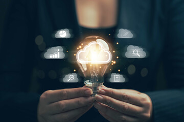 Poster - Light bulb in hand. Big data analysis and business concept with charts and graph icons on digital screen and businessman in the background.