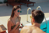 Fototapeta  - Gorgeous young woman in a green bikini holding a fruit cocktail