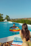 Fototapeta  - A man and a woman enjoying a pool overlooking a scenic town