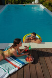 Fototapeta  - A young couple spending a sunny afternoon by their swimming pool