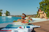 Fototapeta  - Two people basking in the summer sun enjoying a day at the pool.