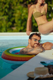 Fototapeta  - A man relaxing in a float on the edge of a swimming pool