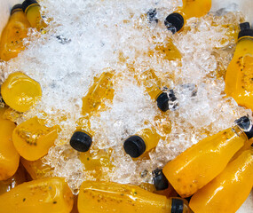 Wall Mural - Freshly squeezed juices in plastic bottles in ice at the market