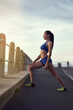 © peopleimages.com - Woman, music and stretching in road with fitness for exercise, getting ready or workout with earphones in city. Athlete, runner and girl with radio for warm up, training and physical activity outdoor