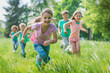 © artefacti - Kids Joyfully Running Together Through Lush Green Grass in the Sun