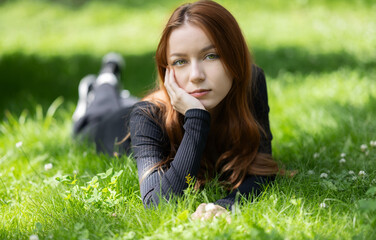 Beautiful girl with red hair enjoying summertime in the park.