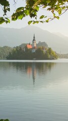 Wall Mural - Lake Bled Slovenia, summer view. Beautiful lake with a Pilgrimage Church on small island during sunrise in Slovenia. Island Bled with the Pilgrimage Church of the Assumption of Maria and Bled Castle