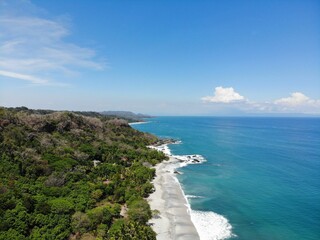 Wall Mural - Aerial view of a turquoise sea against a lush green tropical island