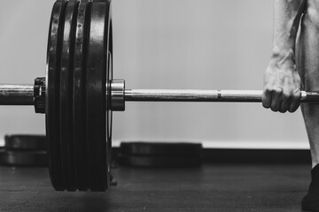 Young adult stands in a gym, ready for their workout, gripping a barbell