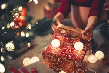 Wall Mural - A close-up shot of a pregnant woman using a golden ribbon to wrap the Christmas presents