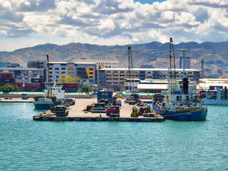 Cebu City, Philippines - May 13, 2024: One of the berths of the port of Cebu, set against the cityscape and nearby mountains.