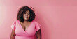 © Nataliia_Trushchenko - A woman with curly hair is wearing a pink dress. Beautiful American African plus-size model wearing a pink dress portrait on a pink background. Body positivity and diversity