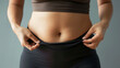 © Trineso - A young woman holding her belly, weight loss, belly fat, body fat, dieting, calorie deficit, exercise, metabolism, fat burning, healthy eating, nutrition, portion control, workout, gym, cardio, streng
