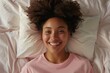 © Deivison - Top view of an African American woman lying down smiling and stretching in bed, morning concept.