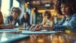 © Trichaiwat - Business meeting with a diverse group of young professionals discussing and taking notes at a modern office conference table.