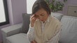 © Krakenimages.com - A mature woman with short hair appears stressed in a cozy living room setting, evoking themes of mental health and wellbeing.